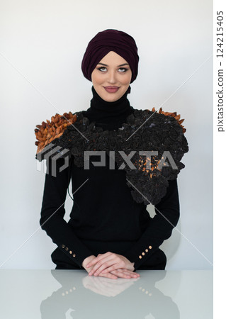 A stylish Muslim woman in a hijab presents her innovative handmade fashion accessory crafted from dried plums in a professional studio. A stylish Muslim woman in a hijab presents her innovative handmade fashion accessory crafted from dried plums in a professional studio. 124215405