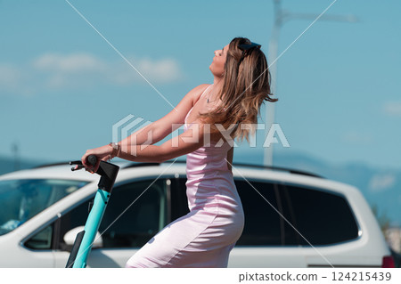 Elegant woman in a pink dress and sunglasses riding an electric scooter through the sunny city streets, embracing the freedom and style of a perfect urban adventure. Elegant woman in a pink dress and sunglasses riding an electric scooter through the sunny city streets, embracing the freedom and style of a perfect urban adventure. 124215439