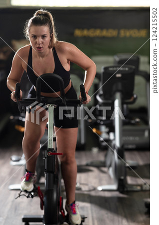 A focused fitness woman performing a conditioning workout in the gym, pushing her limits with strength, determination, and intense dedication. A focused fitness woman performing a conditioning workout in the gym, pushing her limits with strength, determination, and intense dedication. 124215502