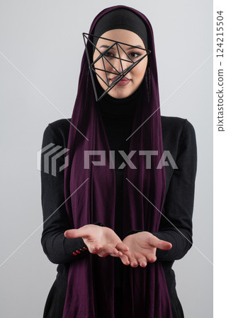 Elegant Muslim woman in a hijab with a geometric structure in a conceptual portrait. 124215504