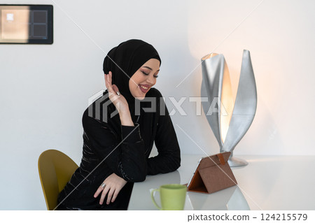 Modern Muslim woman in a hijab working on a tablet at home. Modern Muslim woman in a hijab working on a tablet at home. 124215579
