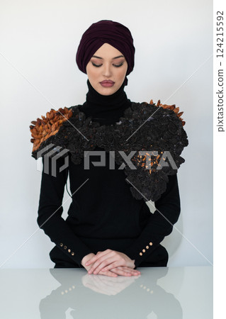 A stylish Muslim woman in a hijab presents her innovative handmade fashion accessory crafted from dried plums in a professional studio. A stylish Muslim woman in a hijab presents her innovative handmade fashion accessory crafted from dried plums in a professional studio. 124215592