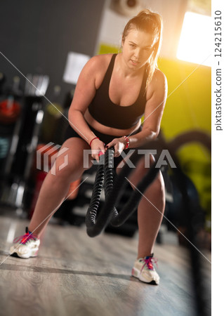 Fit Woman Performing Rope Conditioning Exercise in the Gym 124215610