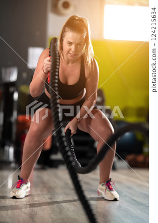 Fit Woman Performing Rope Conditioning Exercise in the Gym 124215634