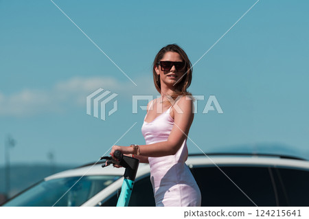 Elegant woman in a pink dress and sunglasses riding an electric scooter through the sunny city streets, embracing the freedom and style of a perfect urban adventure. Elegant woman in a pink dress and sunglasses riding an electric scooter through the sunny city streets, embracing the freedom and style of a perfect urban adventure. 124215641