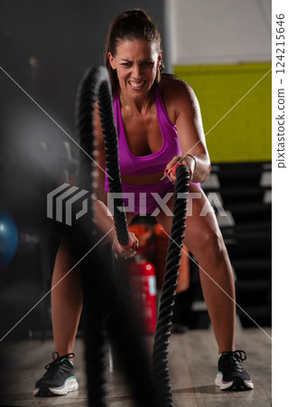 Fit Woman Performing Rope Conditioning Exercise in the Gym 124215646