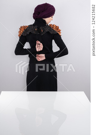 A stylish Muslim woman in a hijab presents her innovative handmade fashion accessory crafted from dried plums in a professional studio. 124215682