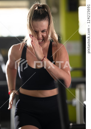 Woman Running on Treadmill in Gym.A fit woman wearing a purple sports outfit is running on a treadmill in a gym. She has a focused yet relaxed expression, with gym equipment and a warm light in the 124215691