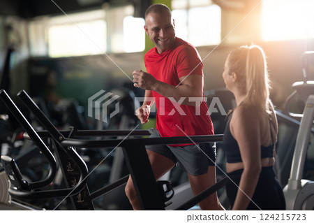 A couple working together in the gym, performing a conditioning workout side by side, supporting each other with strength, motivation, and teamwork. A couple working together in the gym, performing a conditioning workout side by side, supporting each other with strength, motivation, and teamwork. 124215723