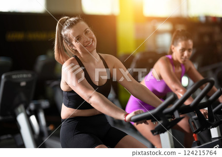 Two fitness women working together on a conditioning workout in the gym, supporting each other with strength, focus, and determination. Two fitness women working together on a conditioning workout in the gym, supporting each other with strength, focus, and determination. 124215764