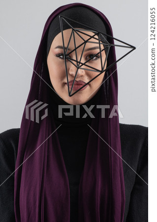 Elegant Muslim woman in a hijab with a geometric structure in a conceptual portrait. 124216055