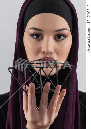 Elegant Muslim woman in a hijab with a geometric structure in a conceptual portrait. 124216243