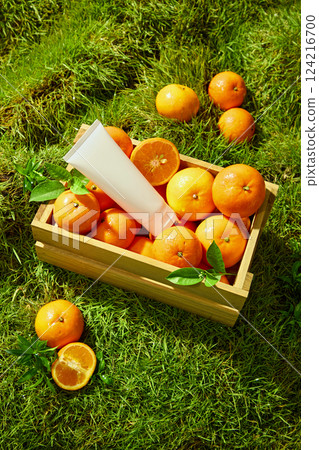 Brightly ripe Citrus Burst Orange placed on a green Meadow background. Unbranded tube of cream used for the design placed among fresh oranges in a wooden crate. Decorated with green orange leaves. Brightly ripe Citrus Burst Orange placed on a green Meadow background. Unbranded tube of cream used for the design placed among fresh oranges in a wooden crate. Decorated with green orange leaves. 124216700