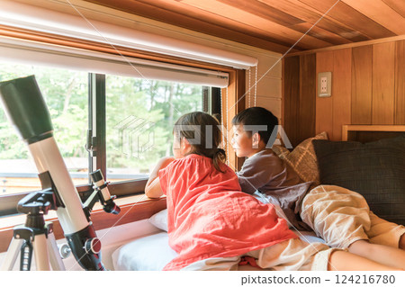 Children, brothers, and sisters playing with a telescope during summer vacation (cottage, villa, mountain hut, camping, glamping) 124216780