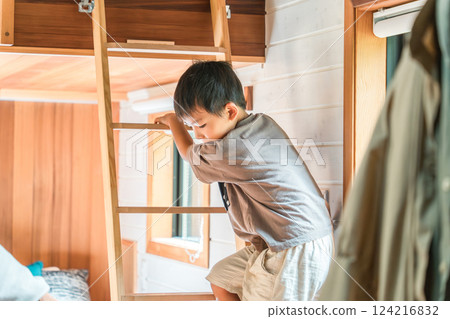 Boy climbing down a ladder in a cottage loft/attic 124216832