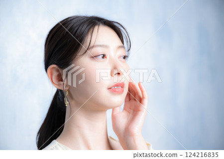 特寫：一位年輕女子，外表光滑透明，在淺藍色背景下關心自己的皮膚。 124216835
