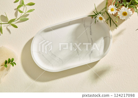 Top view of an oval marble tray presented on white background. Empty marble tray is used to hold the product and design. Branches and flowers around are used for decoration. Empty space for text. 124217098