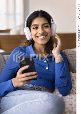 Indian woman wear modern wireless headphones listening popular track Indian woman wear modern wireless headphones listening popular track 124217547