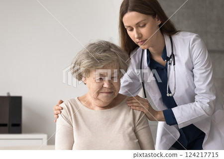 Compassionate female doctor embrace shoulders of sad older female patient Compassionate female doctor embrace shoulders of sad older female patient 124217715