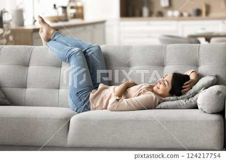 Peaceful smiling young girl lying on sofa in comfortable pose Peaceful smiling young girl lying on sofa in comfortable pose 124217754