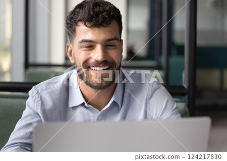 Smiling handsome freelancer working on laptop in coworking space 124217830