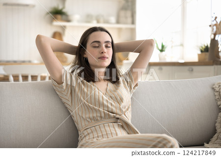 Serene carefree young woman relax on sofa keep eyes closed 124217849