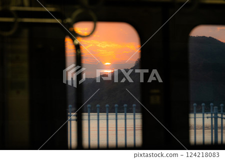 Image of watching the sunset from inside a quiet train car with a view of the sea 124218083