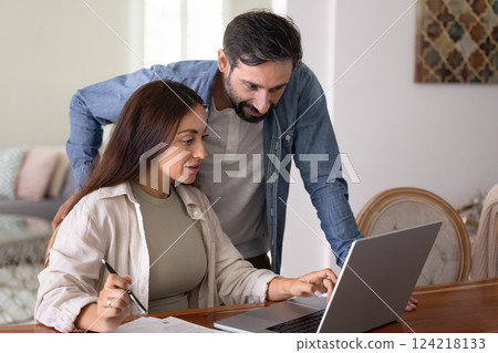 Positive husband and wife using online bank application on laptop Positive husband and wife using online bank application on laptop 124218133