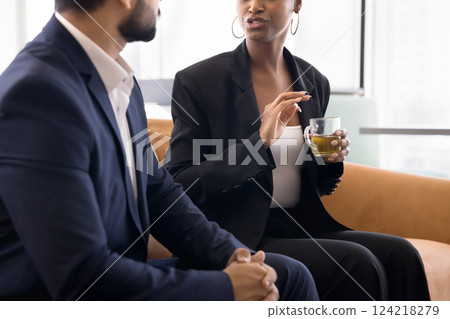 African woman holding tea cup discuss work-related matters with workmate 124218279