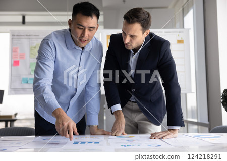 Two diverse business colleagues brainstorming on project statistic data together 124218291
