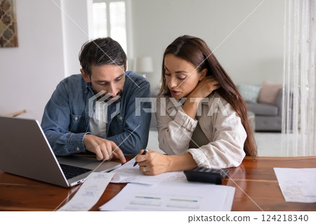 Serious young middle aged couple analyzing personal domestic budget Serious young middle aged couple analyzing personal domestic budget 124218340