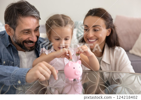 Happy parents training little kid girl to save money 124218402