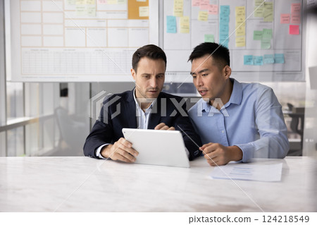 Serious Latin businessman consulting male Asian business expert Serious Latin businessman consulting male Asian business expert 124218549