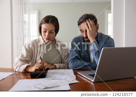 Concerned young middle aged couple counting expenses Concerned young middle aged couple counting expenses 124218577