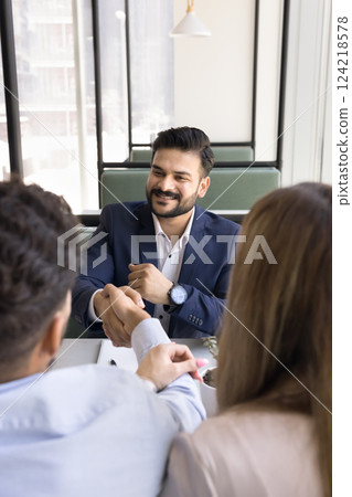 Business professional in suit shaking hands with two colleagues Business professional in suit shaking hands with two colleagues 124218578
