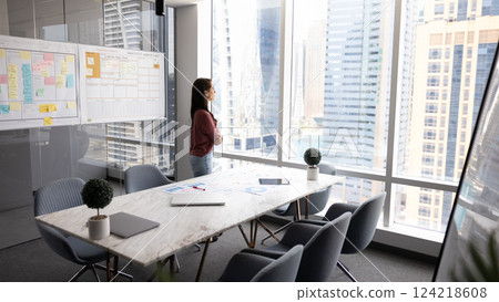 Thoughtful young business leader woman standing alone in office 124218608