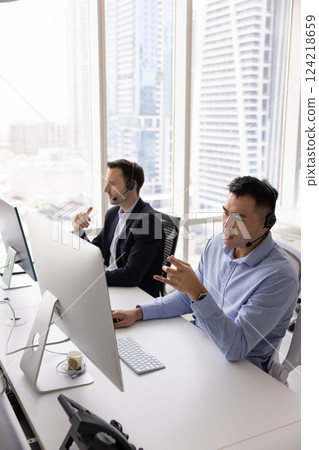 Serious busy Asian telemarketing agent man talking to client Serious busy Asian telemarketing agent man talking to client 124218659