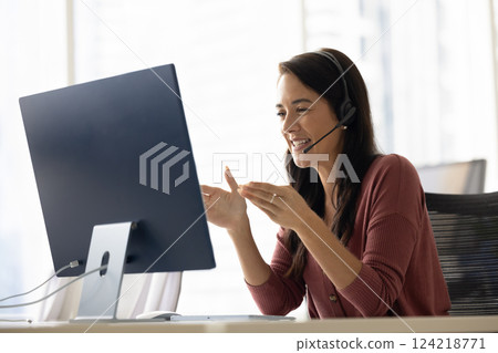 Positive Latin businesswoman in headphones talking on video call 124218771