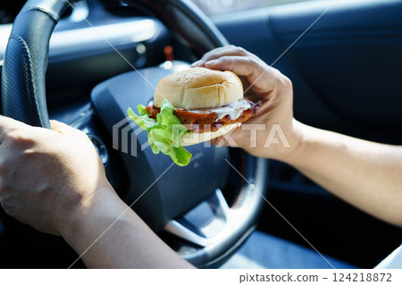 Asian woman driver hold and eat hamburger food in car. 124218872