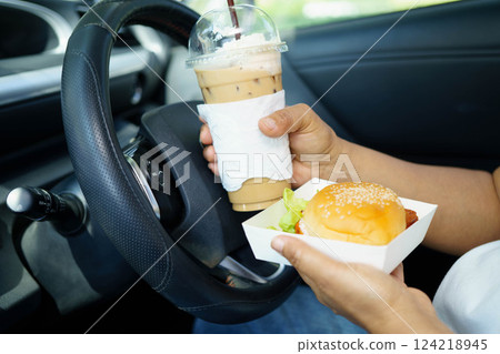 Asian woman driver hold and eat hamburger food in car. 124218945