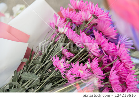 A bouquet of pink flowers sits on a table. The flowers are arranged in a way that makes them look like they are in a vase. 124219610