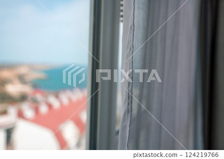 Window View Blinds: Coastal town seen through hotel window during daytime for relaxation. 124219766