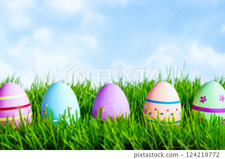 Bright Easter Egg Hunt Five Vibrant, Colorful Eggs In Lush Green Grass Under Blue Springtime Sky Pink, Purple, Peach More 124219772