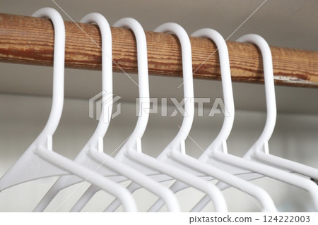 white plastic clothes hangers in closet 124222003