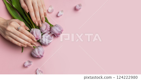 Woman showing stylish nude manicure with spring tulips on pink background 124222980