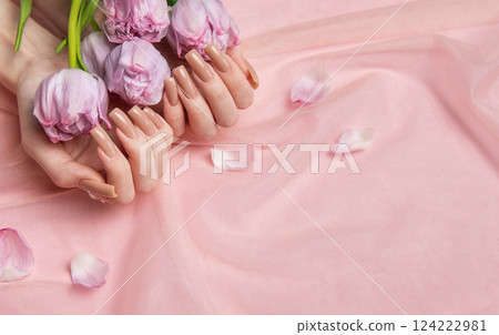 Woman hands holding pink tulips showing nude manicure on pink background 124222981