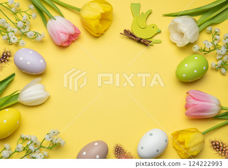 Easter eggs and tulips framing yellow background with wooden bird celebrating spring holidays 124222993