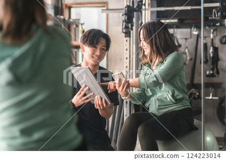 一名女子和她的教練在健身房鍛鍊、運動、舉重、節食和訓練 一名女子和她的教練在健身房鍛鍊、運動、舉重、節食和訓練 124223014