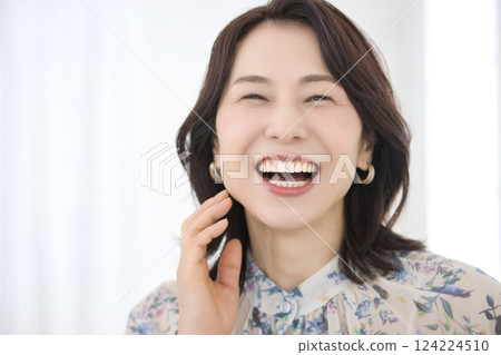 A smiling middle-aged woman wearing a floral blouse 124224510