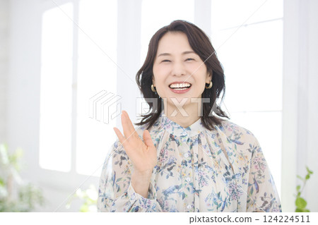A smiling middle-aged woman wearing a floral blouse 124224511